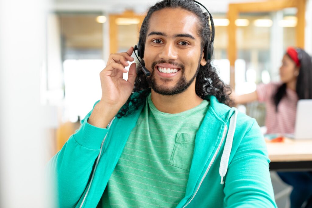 Happy African-american male customer service executive looking at camera and talking on headset